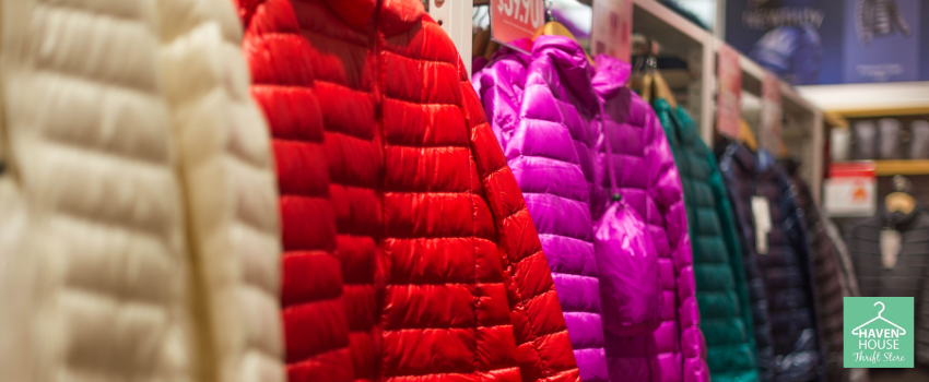 Colorful assorted puffer jackets displayed on a thrift store.