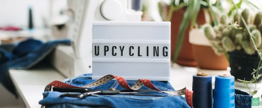 HHTS-A sign on top of denim jeans surrounded by threads and sewing tools